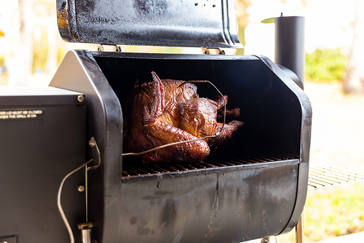 A rotisserie chicken being cooked on a grill.